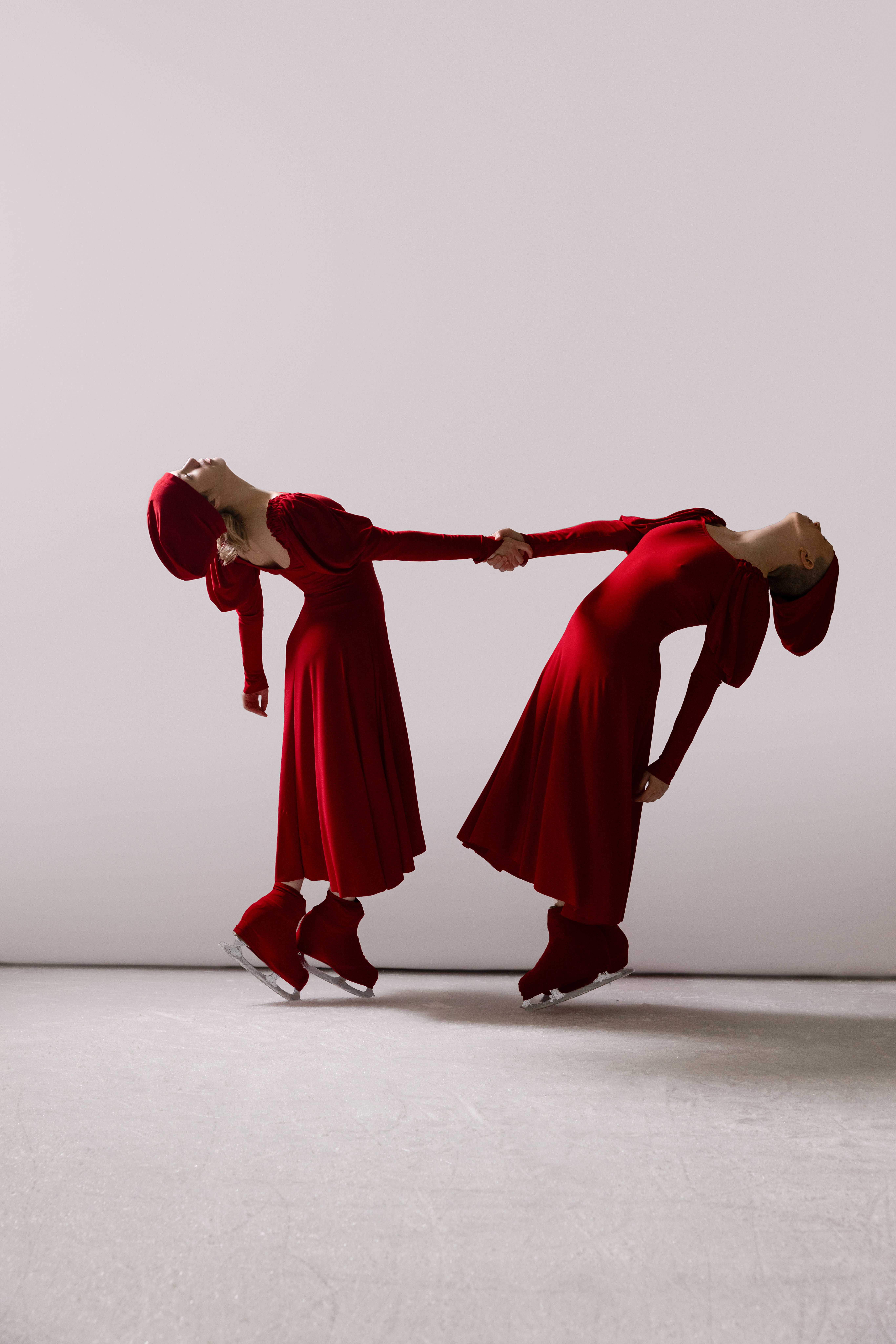 Two skaters in red, arching backward, connected at hands